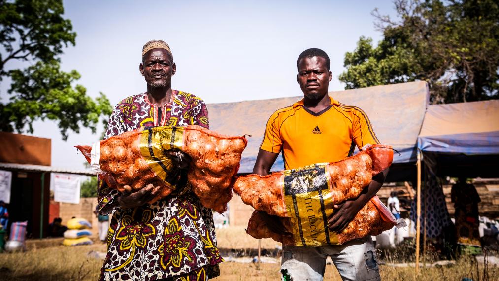 Deux hommes au Burkina Faso transportant des sacs d'oignons