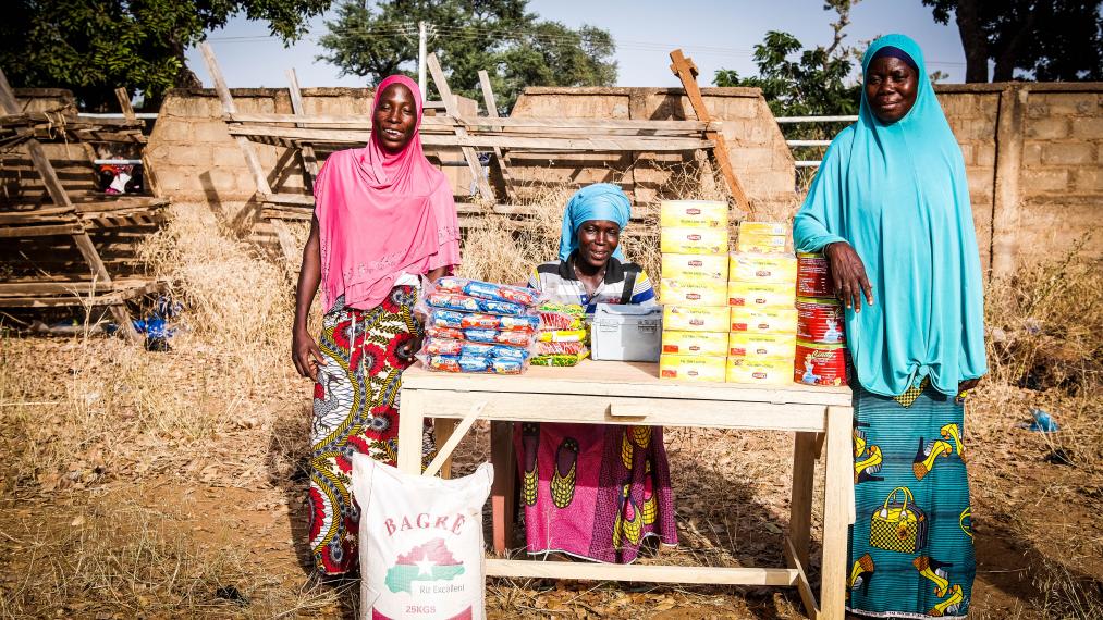 3 femmes souriantes au Burkina Faso tenant leur magasin en extérieur